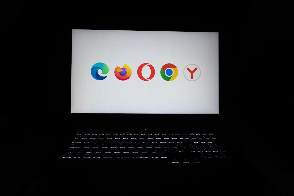 Les logos de cinq navigateurs web affichés sur l’écran d’un ordinateur portable, dans la pénombre