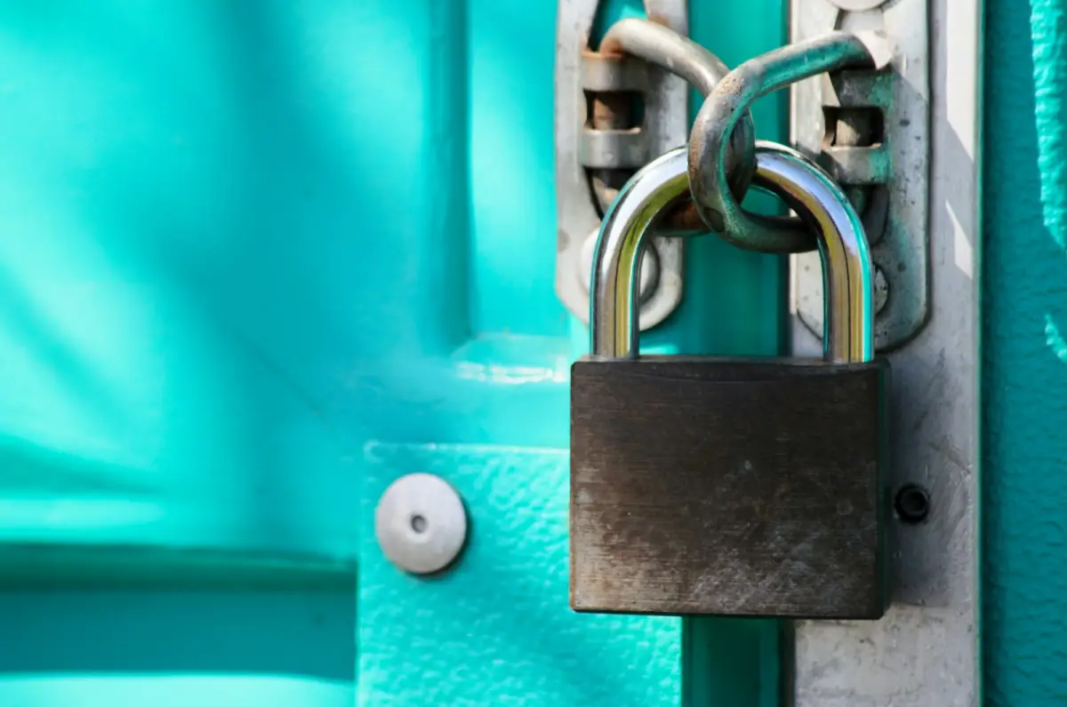 Un cadenas fermé sur le loquet d’une porte peinte en turquoise